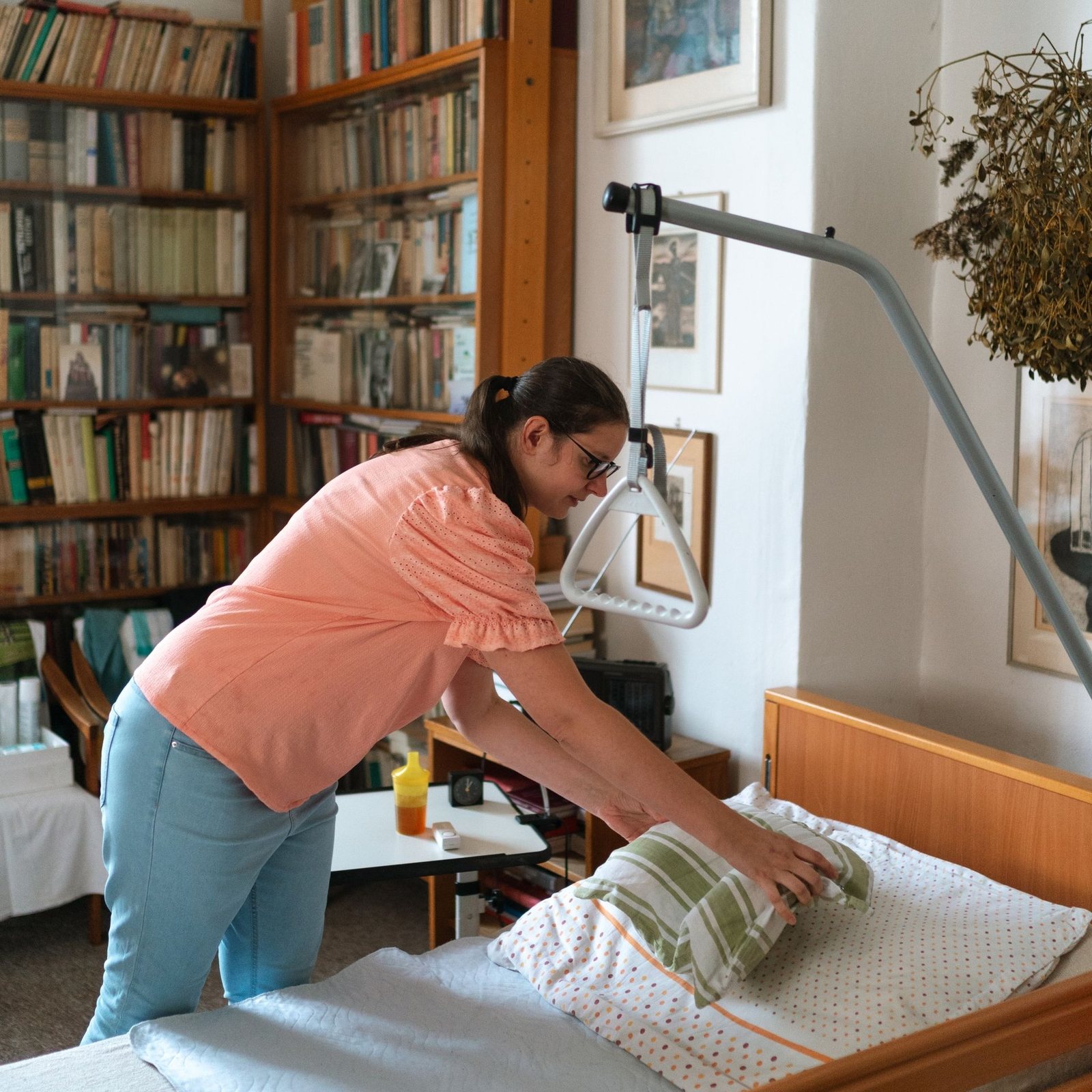 Caregiver smoothing the bedding on an adjustable bed