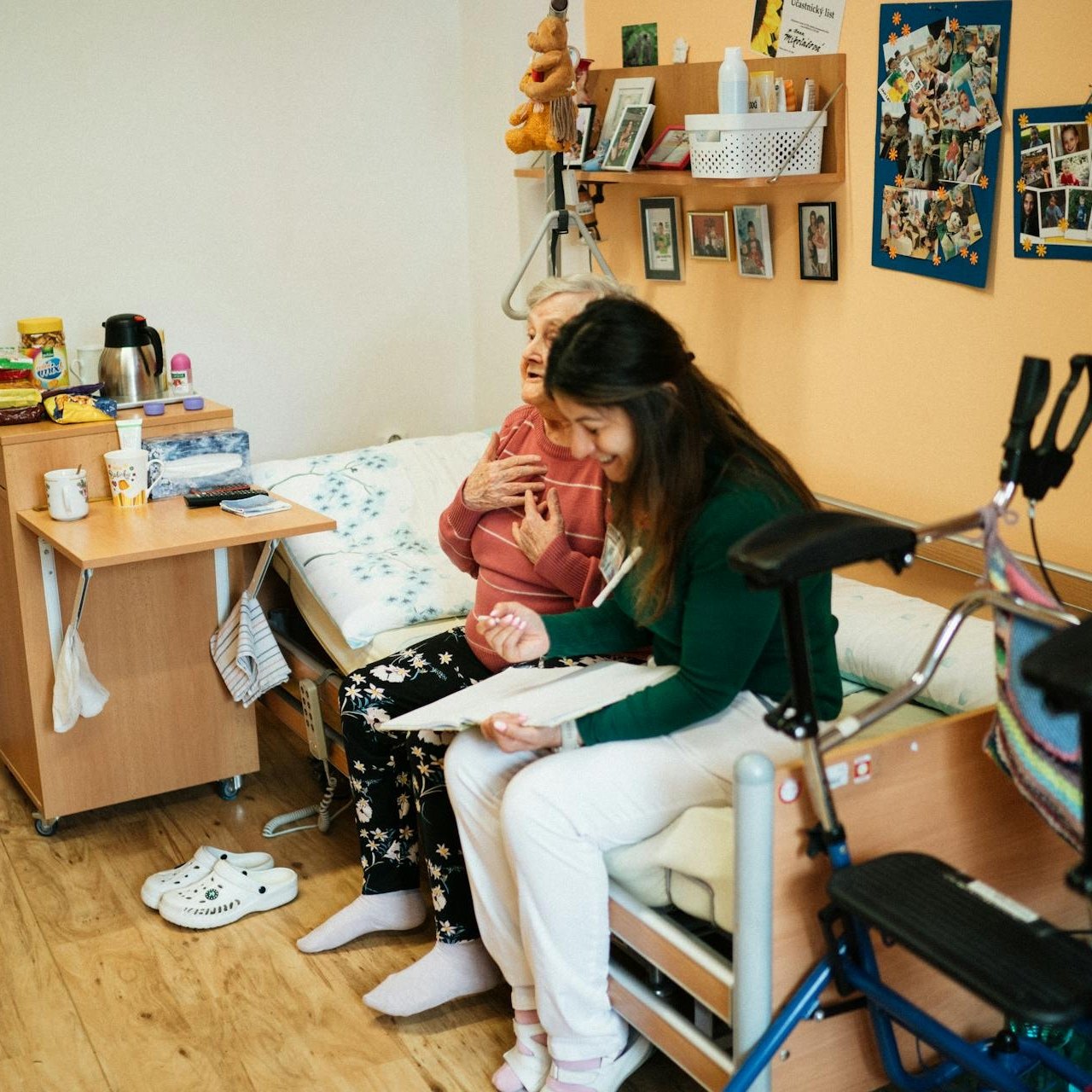 Caregiver reading quietly at an older woman’s bedside