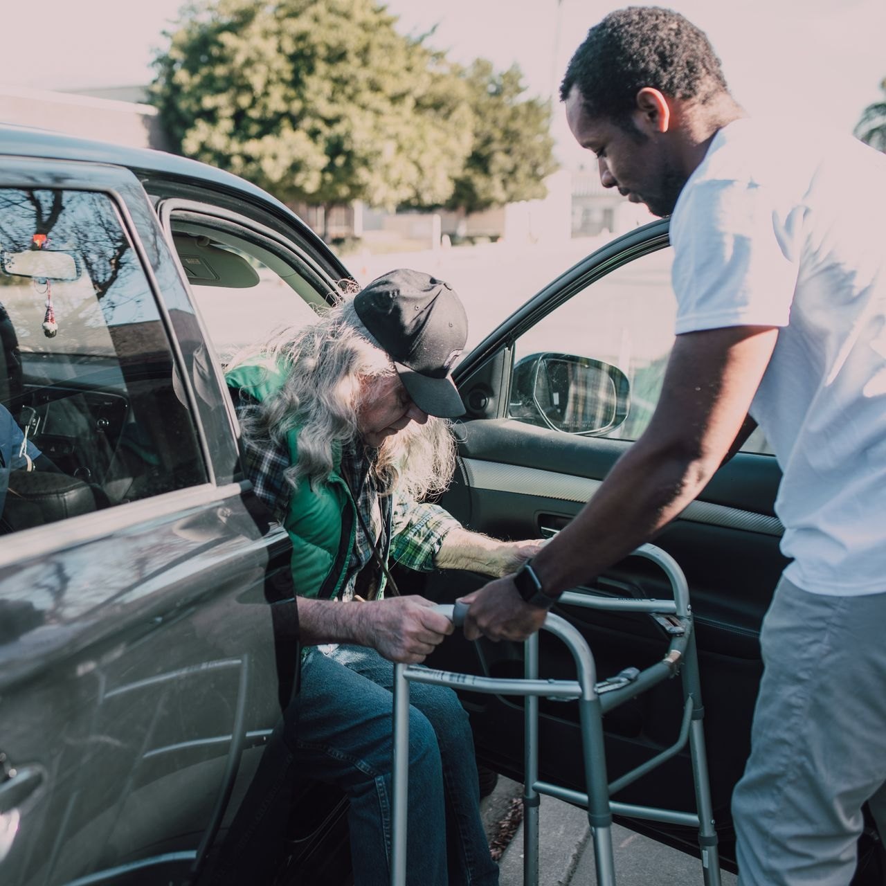 Caregiver holding the walker steady beside the car