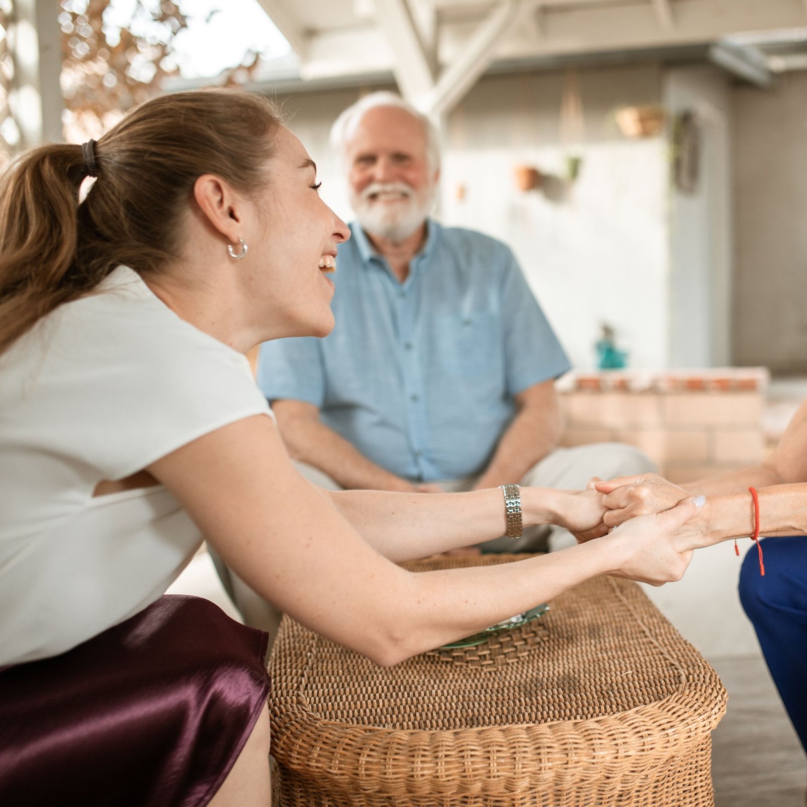 Caregiver holding hands with a smiling couple on their back patio