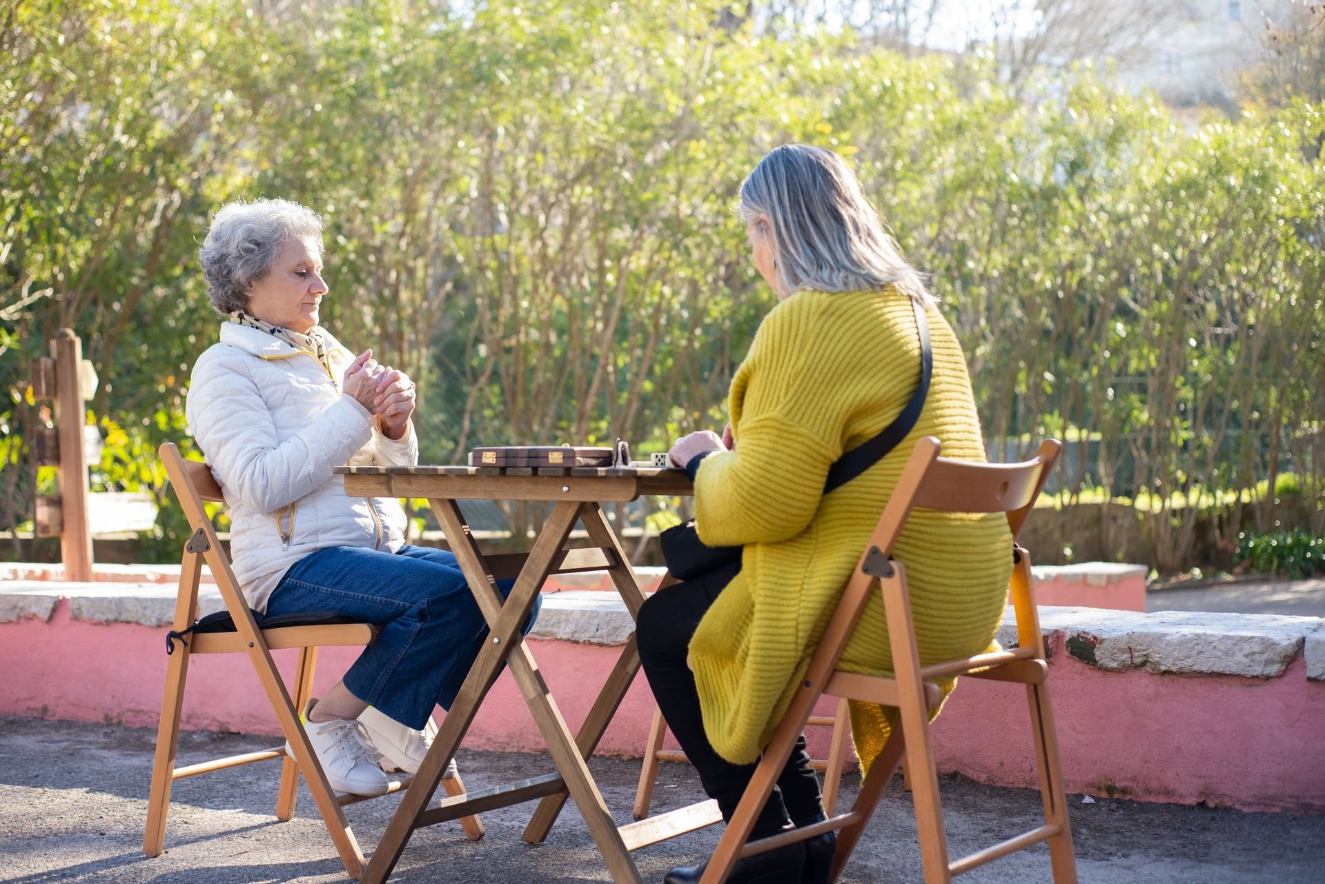 Caregiver and an older woman talking together at a garden table