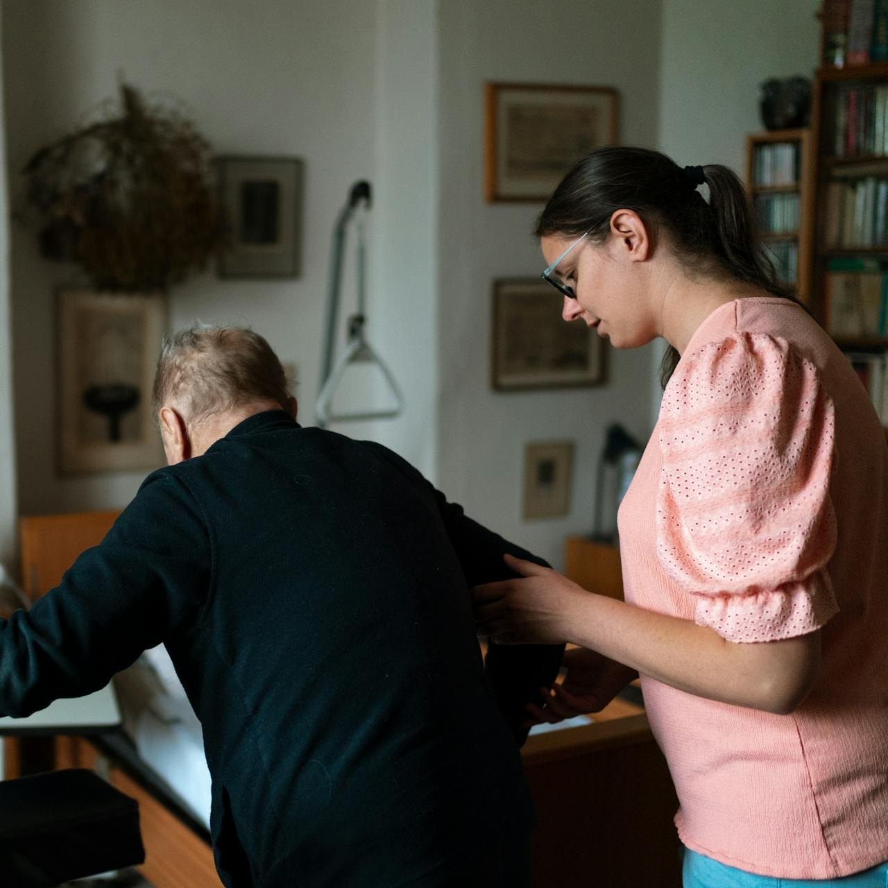 Caregiver supporting an older man as he stands
