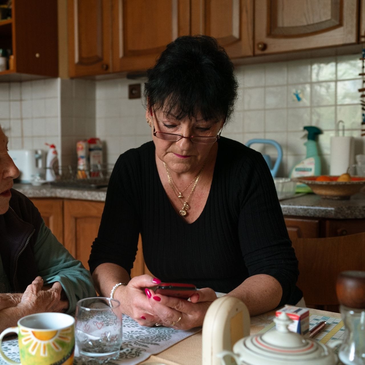 An older woman and her caregiver looking at something on a phone together