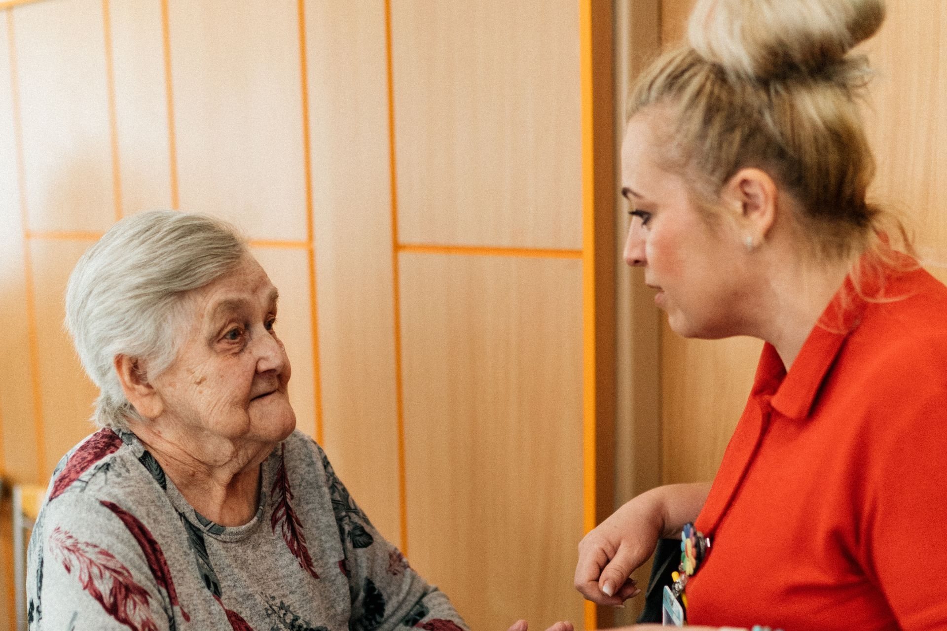 Caregiver leaning in to talk with an older woman