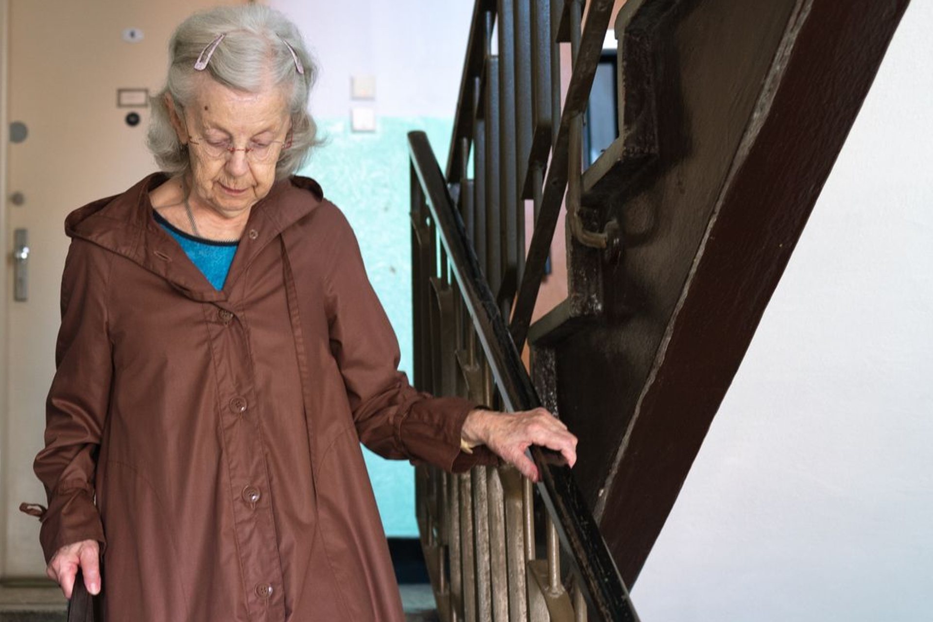 An older woman coming down the stairs, one hand on the rail