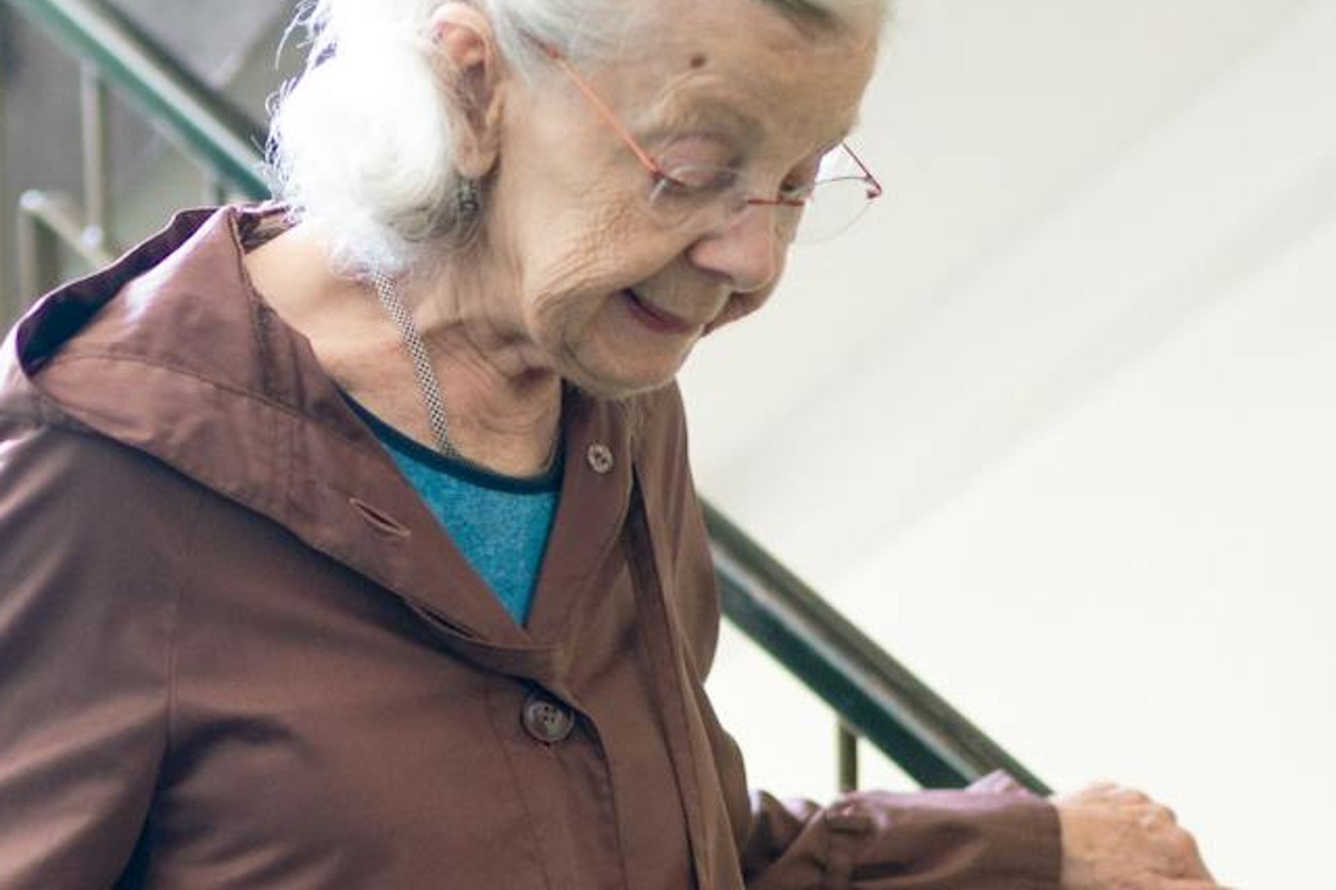 An older woman taking the stairs with a hand on the rail