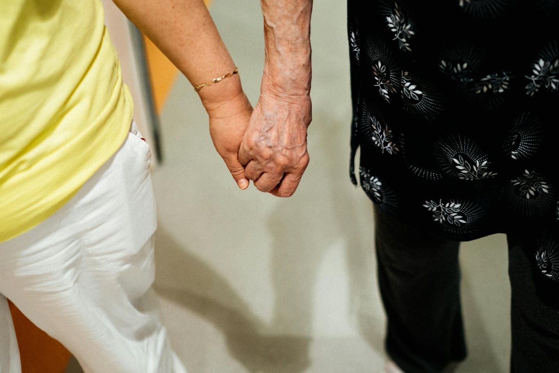 Caregiver and an older person walking hand in hand